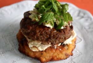 Photo of open faced burger on couscous cake with labne and fresh mint