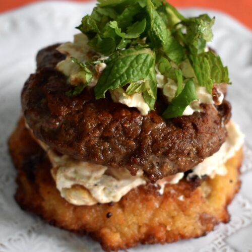 Photo of open faced burger on couscous cake with labne and fresh mint